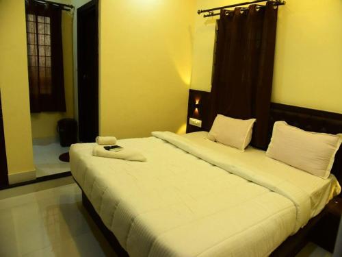 a bedroom with two beds with white sheets at MG Residency in Chikmagalūr