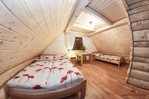 Un dormitorio con una cama con flores rojas. en Domek Łemkowski, en Ustrzyki Dolne