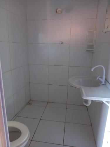 a white bathroom with a toilet and a sink at Paracuru HolaOnda WaveHostel in Paracuru