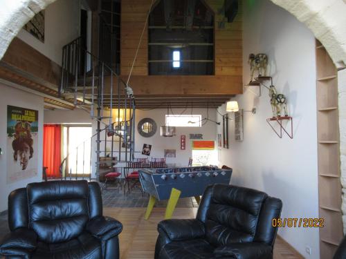 a living room with two leather chairs and a ping pong table at Interludes Normands in Ver-sur-Mer