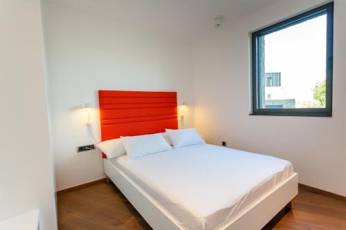 une chambre avec un lit blanc avec une tête de lit rouge dans l'établissement Family-friendly apartments with swimming pool Vantacici, Krk - 19403, à Malinska