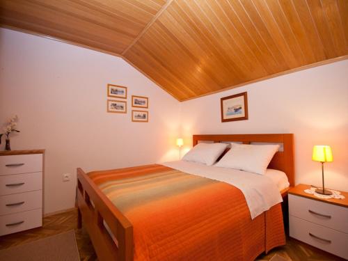sypialnia z łóżkiem i drewnianym sufitem w obiekcie Apartments and rooms with parking space Baska, Krk - 19424 w Bašce