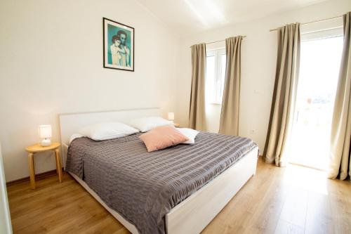 1 dormitorio con 1 cama con edredón gris y blanco en Seaside holiday house Sumartin, Brac - 19444, en Sumartin