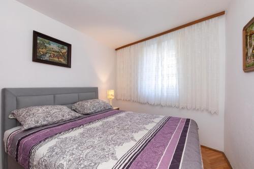 a bedroom with a bed and a window at Apartments by the sea Baska, Krk - 19517 in Baška