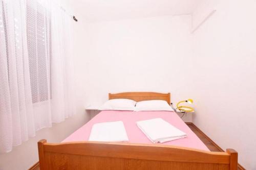 um quarto com uma cama com lençóis cor-de-rosa e almofadas brancas em Apartments with a parking space Sabunike, Zadar - 19695 em Privlaka