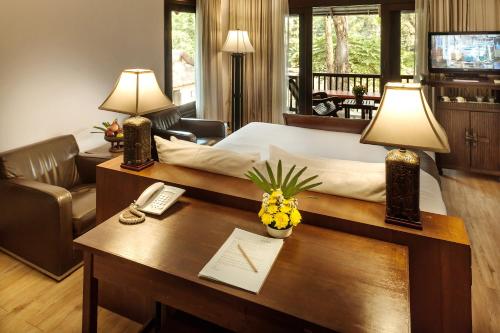 a hotel room with a bed and a desk with a desk at Lanna Dusita Riverside Boutique Resort in Chiang Mai