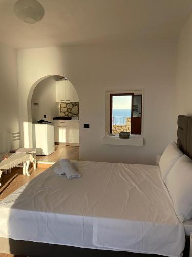 a white bedroom with a large bed and a window at Vila Dena in Vlorë