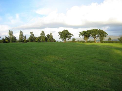 a large green field with trees in the distance at Stable Lodge in Drymen