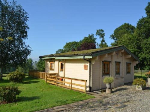 a small white house with a wooden fence at Stable Lodge in Drymen