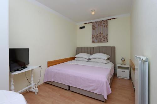 1 dormitorio con 1 cama, escritorio y TV en Apartments with a parking space Kostrena, Rijeka - 19470, en Kostrena