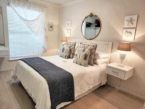 a bedroom with a bed with a mirror and a window at The Potting Shed Self Catering in Hermanus