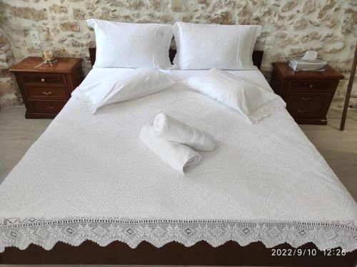a large white bed with white sheets and pillows at Xenonas "Alexandra's Coffee House" in Volimes