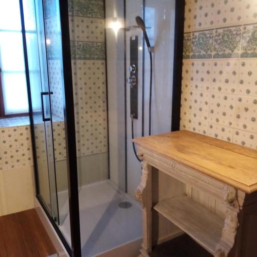 une douche avec une porte en verre à côté d'une table dans l'établissement gitedubourghaut, à Saint-Éloy-les-Tuileries