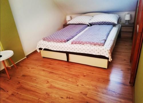 a bed in a room with a wooden floor at Pitypang Apartman in Gyula