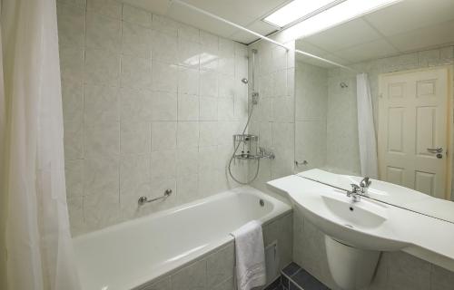 Hotel Nona في البينا: حمام أبيض مع حوض وحوض ومغسلة