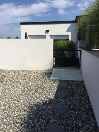 a house with a white wall and a gravel driveway at Maison contemporaine à Caudan in Caudan