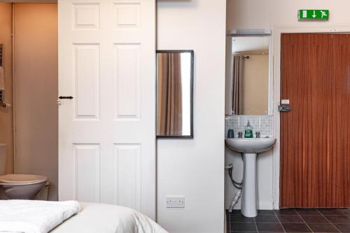 a bathroom with a bed and a sink and a toilet at City Centre Guest House - Gloucester Park in Gloucester