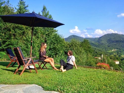 two women sitting on the grass under an umbrella at Chalet Alma in Frabosa Sottana