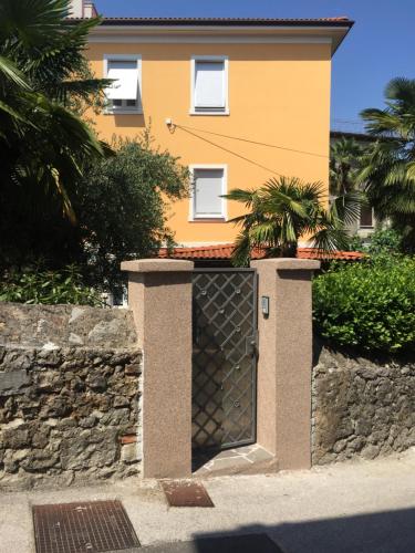 a yellow house with a gate and a stone wall at Vallelosca Garden in Opatija