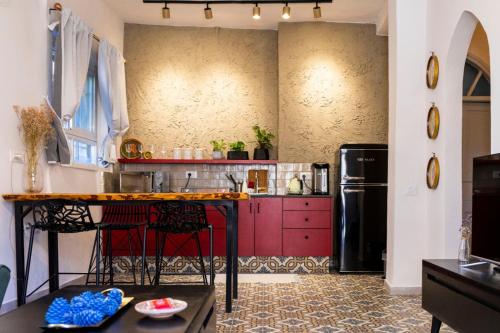 eine Küche mit roten Schränken und einem schwarzen Kühlschrank in der Unterkunft Lulia in Jerusalem