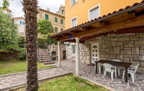 a patio with a table and chairs and a stone wall at Vallelosca Garden in Opatija