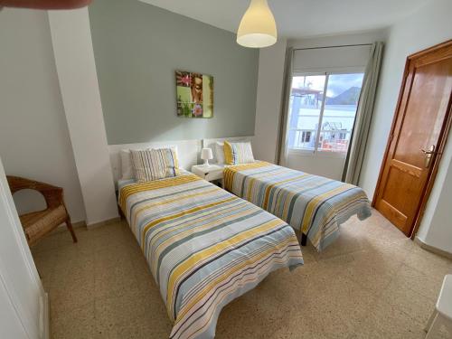 two beds in a room with a window at Las Brisas Mogan Apartamentos in Puerto de Mogán