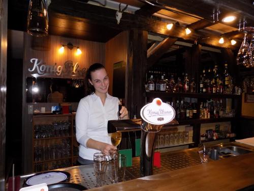 a woman standing behind a bar with a glass of wine at Heidehotel Jagdhof Dobra GmbH in Dobra