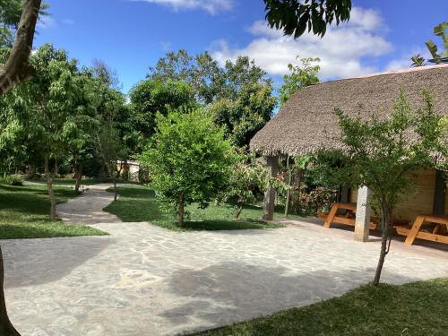 a resort with a straw roofed building with a sandy path at Maison entière ChezSoa, antananarivo in Andoharanofotsy