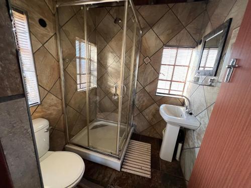 a bathroom with a shower and a toilet and a sink at Intundla's Rest in Marloth Park