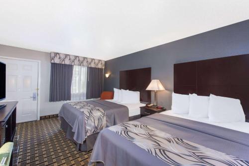 a hotel room with two beds and a flat screen tv at Days Inn by Wyndham Ennis in Ennis