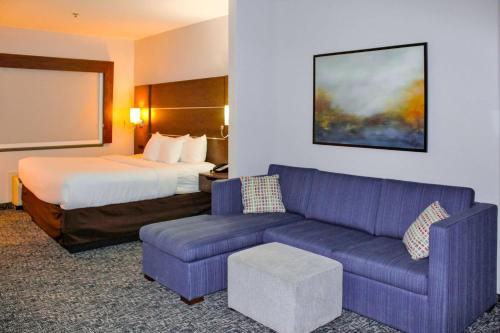 a hotel room with a bed and a purple couch at Comfort Inn & Suites Near Lake Guntersville in Scottsboro