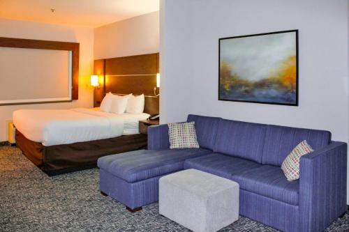 a hotel room with a bed and a purple couch at Comfort Inn and Suites Near Lake Guntersville in Scottsboro