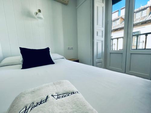 a white bed with a blue pillow and a window at Veracruz Puerta del Sol in Madrid