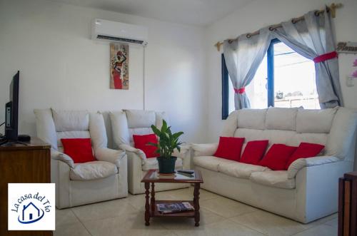 una sala de estar con 2 sofás blancos y almohadas rojas en La casa del tio 1, en Colonia del Sacramento