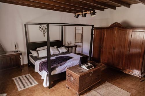 Apartamento Los Lirios في سانتا بريخيذا: غرفة نوم مع سرير مظلة وخزانة خشبية