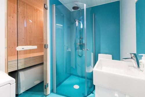 a blue bathroom with a shower and a sink at Bruksvallarna - Modern fjällstuga med panoramautsikt och WiFi in Bruksvallarna