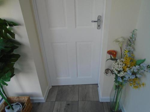 a vase of flowers sitting next to a door at The Mews in Erith