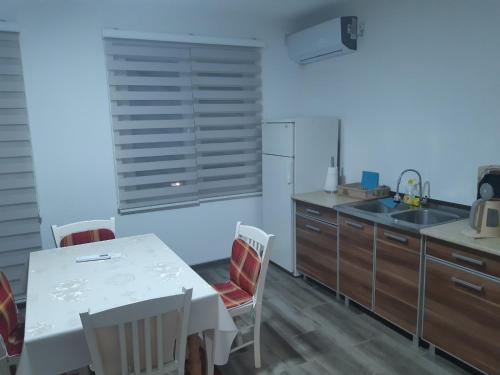 uma cozinha com uma mesa e cadeiras brancas e um lavatório em AS guesthouse em Krževići