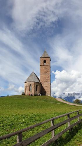 an old church on top of a hill with a fence at Marlingsuites - Vinea - Wieser Josef - Marling in Marlengo