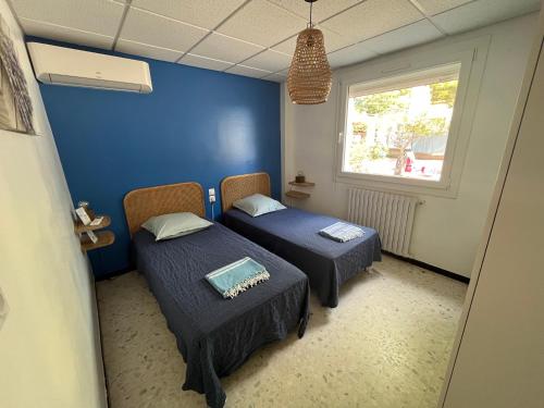 two beds in a room with a blue wall at Meublé tourisme 4*, les pieds dans l'eau, Villa LAS PALMERAS in La Londe-les-Maures
