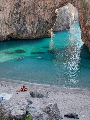 a man laying on a beach next to the water at B&B Civico 64 Scalea in Scalea