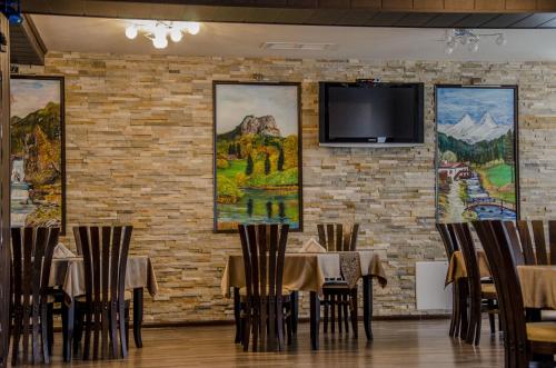 a dining room with tables and a tv on a brick wall at Rubis Hotel in Rudozem