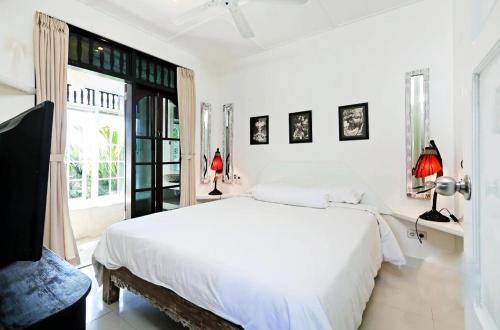 Blue Lagoon Apartment 3br في كوتا: غرفة نوم بيضاء مع سرير كبير ونافذة
