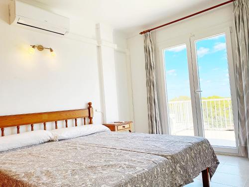 - une chambre avec un lit et une grande fenêtre dans l'établissement Apartaments Marina Sol i Pins, à Cala Figuera