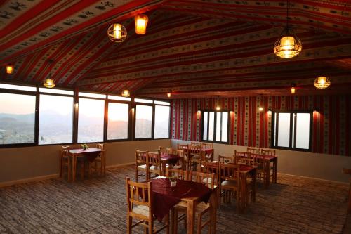 a dining room with tables and chairs and windows at Petra Wooden House in Wadi Musa
