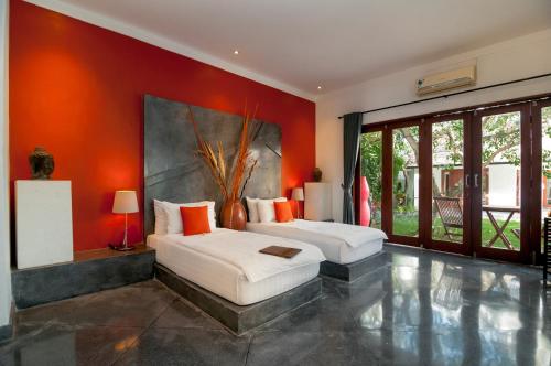 2 Betten in einem Zimmer mit orangefarbenen Wänden in der Unterkunft Villa Andaman in Canggu