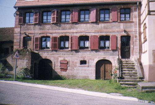 an old building with red shuttered windows and a door at Chambre d'Hôtes chez Nadine Hamm in Weiterswiller