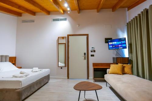 a bedroom with a bed and a couch and a tv at Hotel Semajo in Vlorë