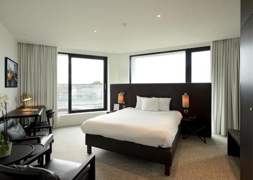 a hotel room with a bed and a desk and windows at Parkhotel Kortrijk in Kortrijk