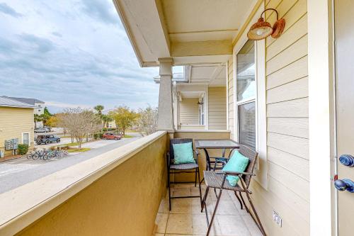 a balcony with chairs and a table with a view of a street at Topsail Village Away on Wildflower in Santa Rosa Beach